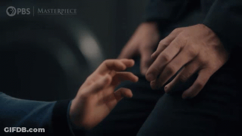 A Man In A Suit And Tie Stands Next To A Woman In A Room With The Words Pbs Masterpiece On The Bottom Right GIF