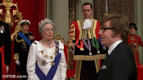 A Man In A Suit And Tie Stands Next To A Woman In A White Dress GIF