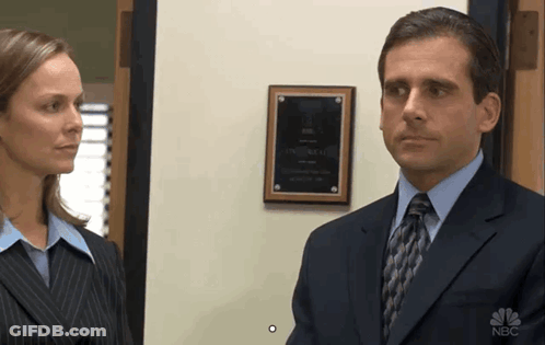 A Man In A Suit And Tie Stands Next To A Woman In Front Of A Plaque That Says Nbc GIF