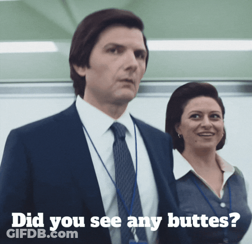 A Man In A Suit And Tie Stands Next To A Woman With The Words " Did You See Any Butts " Written Below Him GIF