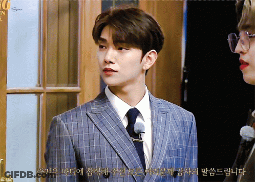 A Man In A Suit And Tie Stands Next To Another Man In Glasses And Red Lipstick GIF