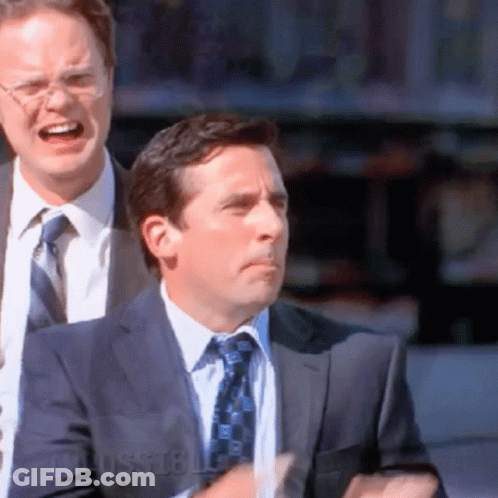A Man In A Suit And Tie Stands Next To Another Man With Glasses GIF