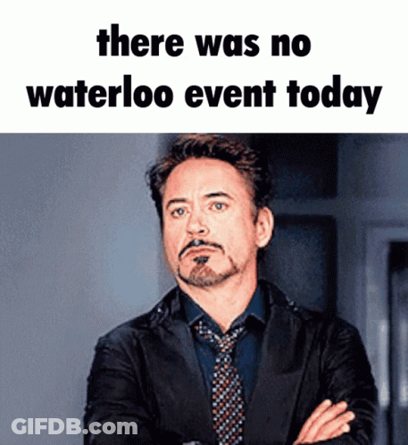 A Man In A Suit And Tie Stands With His Arms Crossed Under A Meme That Says There Was No Waterloo Event Today .. GIF