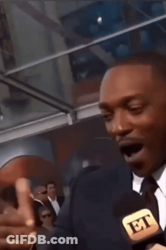 A Man In A Suit And Tie Talking Into A Microphone That Says Et GIF