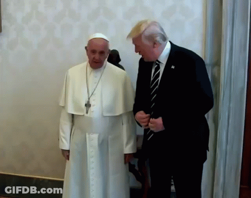 A Man In A Suit And Tie Talks To A Man In A White Robe GIF