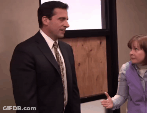 A Man In A Suit And Tie Talks To A Woman In A Purple Vest GIF