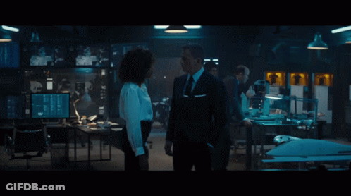 A Man In A Suit And Tie Talks To A Woman In A White Shirt GIF