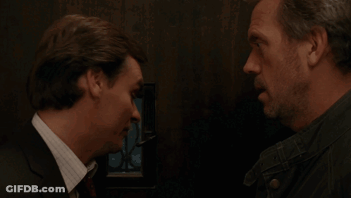 A Man In A Suit And Tie Talks To Another Man In A Black Jacket GIF