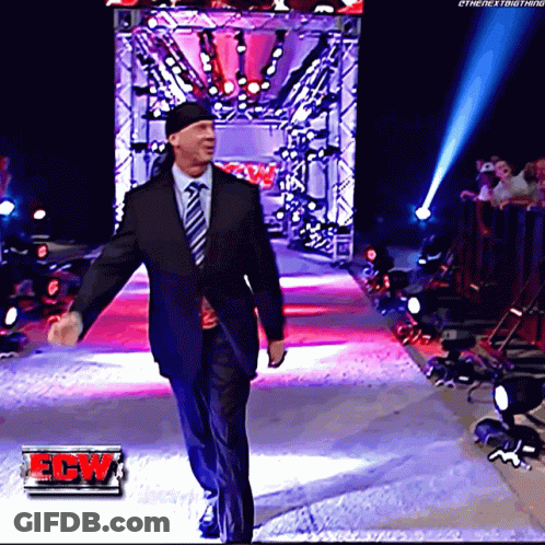 A Man In A Suit And Tie Walks Down A Red Carpet With A Ew Logo In The Corner GIF