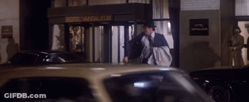 A Man In A Suit And Tie Walks In Front Of A Hotel Vandaleur GIF