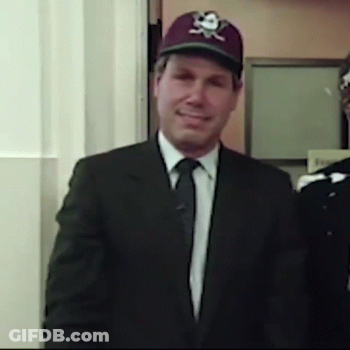 A Man In A Suit And Tie Wearing A Baseball Cap With A Skull And Crossbones On It GIF