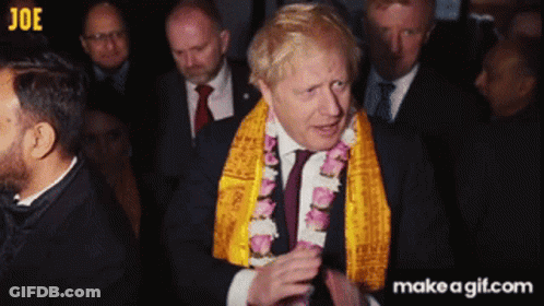 A Man In A Suit And Tie Wearing A Yellow Scarf Around His Neck GIF
