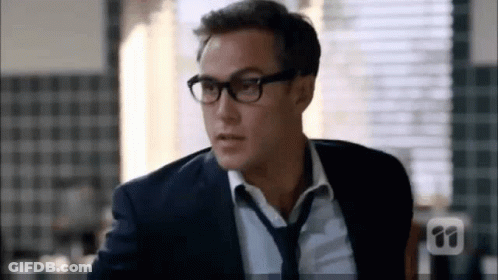 A Man In A Suit And Tie Wearing Glasses And A Tie . GIF