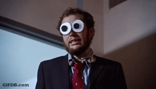 A Man In A Suit And Tie Wearing Googly Eyes GIF