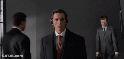 A Man In A Suit And Tie Wearing Headphones Stands In A Dark Room GIF