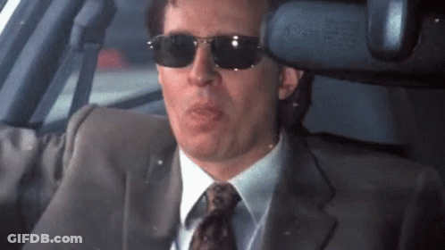 A Man In A Suit And Tie Wearing Sunglasses GIF