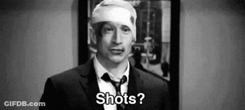 A Man In A Suit And Tie With A Bandage On His Head Is Asking Shots . GIF