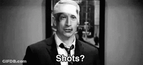 A Man In A Suit And Tie With A Bandage On His Head Is Asking Shots . GIF