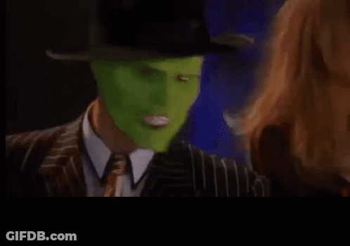 A Man In A Suit And Tie With A Green Mask On His Face Is Making A Funny Face . GIF