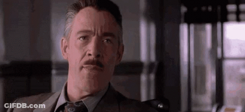 A Man In A Suit And Tie With A Mustache Is Making A Funny Face . GIF