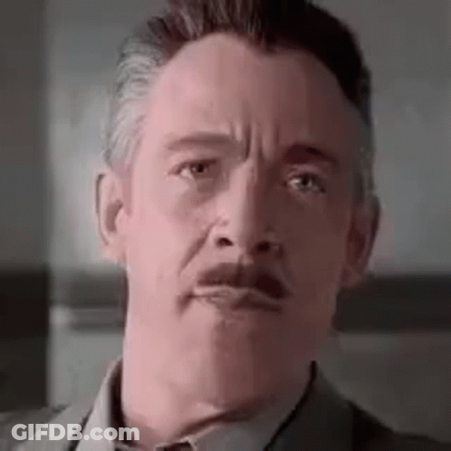 A Man In A Suit And Tie With A Mustache Is Making A Funny Face . GIF