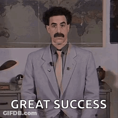 A Man In A Suit And Tie With A Mustache Is Standing In Front Of A Map And Says Great Success . GIF