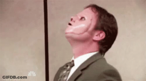 A Man In A Suit And Tie With A Red Face Painted On His Face . GIF