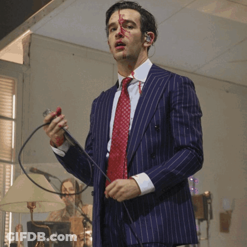 A Man In A Suit And Tie With Blood On His Face GIF