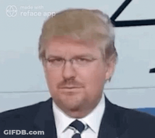 A Man In A Suit And Tie With Glasses And A Beard Is Making A Funny Face . GIF
