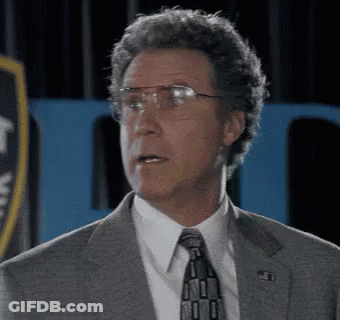 A Man In A Suit And Tie With Glasses Is Making A Funny Face . GIF