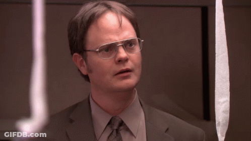 A Man In A Suit And Tie With Glasses Looks At Something GIF