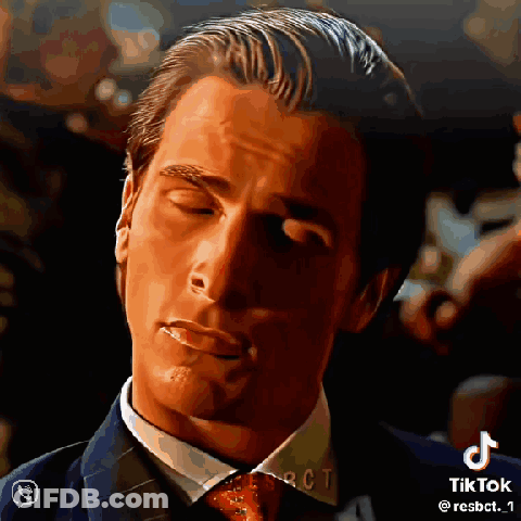 A Man In A Suit And Tie With His Eyes Closed And A Cigarette In His Mouth . GIF