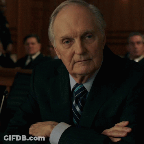 A Man In A Suit And Tie With His Hands Folded GIF