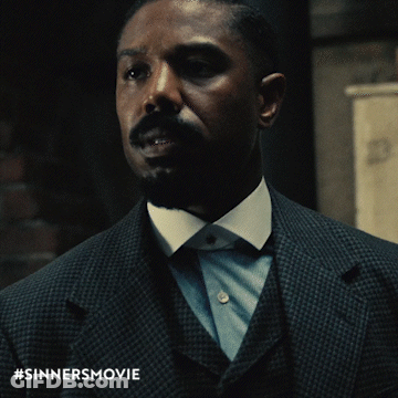 A Man In A Suit And Tie With The Hashtag #Sinnersmovie GIF