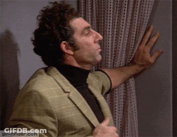 A Man In A Suit And Turtleneck Is Looking Out A Window With A Gif-Finder.com Watermark In The Corner GIF