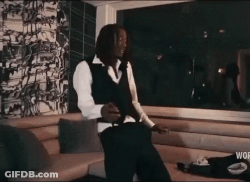 A Man In A Suit And Vest Is Standing In A Living Room Smoking A Cigarette . GIF