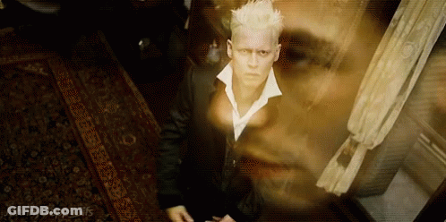 A Man In A Suit And White Collared Shirt Is Standing In A Room With A Ghost Behind Him . GIF