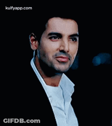 A Man In A Suit And White Shirt Is Looking At The Camera With A Serious Look On His Face . GIF