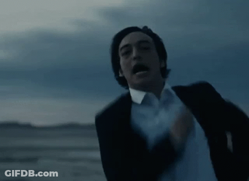 A Man In A Suit And White Shirt Is Running In The Desert With His Mouth Open . GIF