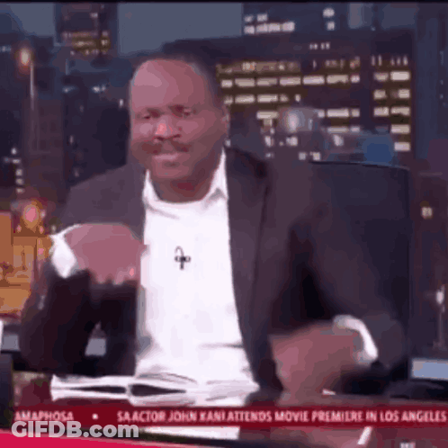 A Man In A Suit And White Shirt Is Sitting In Front Of A Tv Screen That Says Amaphorsa GIF