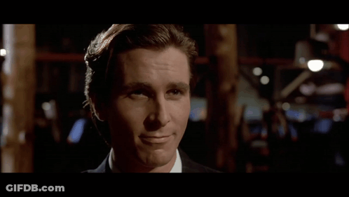 A Man In A Suit And White Shirt Is Smiling And Looking At The Camera GIF
