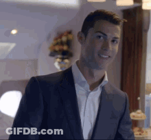 A Man In A Suit And White Shirt Is Smiling In A Room . GIF