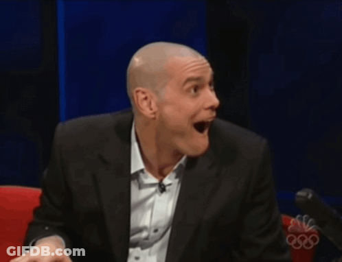 A Man In A Suit And White Shirt Is Smiling In Front Of A Nbc Logo GIF