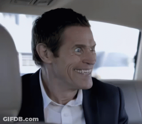 A Man In A Suit And White Shirt Is Smiling In The Back Of A Car GIF