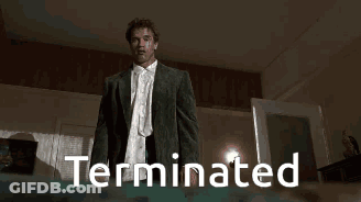 A Man In A Suit And White Shirt Is Standing In A Room With The Word Terminated On The Bottom GIF