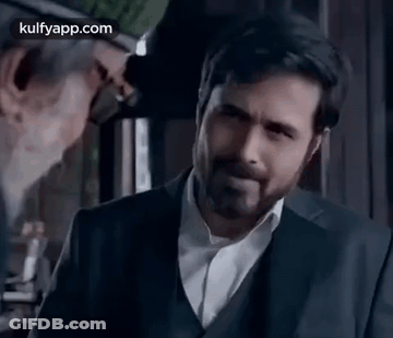 A Man In A Suit And White Shirt Is Standing In Front Of A Mirror . GIF