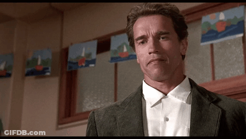A Man In A Suit And White Shirt Is Standing In Front Of A Window With Sailboats On It . GIF