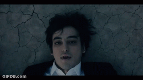 A Man In A Suit And White Shirt Laying On The Ground GIF