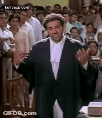 A Man In A Suit And Wig Is Giving A Speech In Front Of A Crowd Of People . GIF