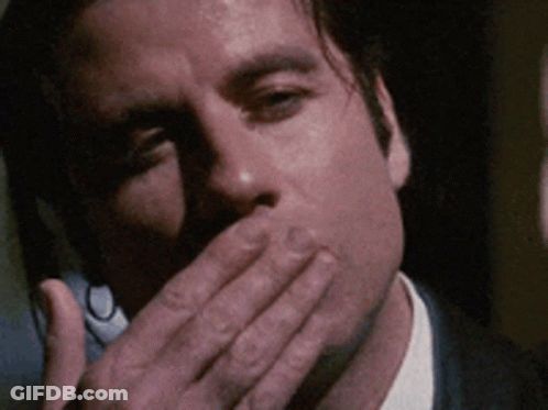 A Man In A Suit Covering His Mouth With His Hand GIF
